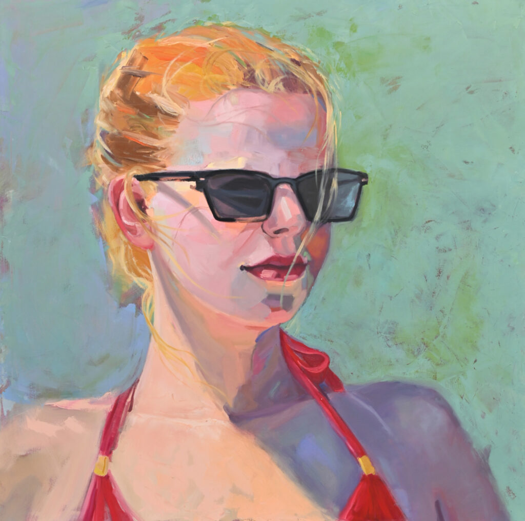 Young woman with blonde hair pulled back, wearing sunglasses and a red bathing suit