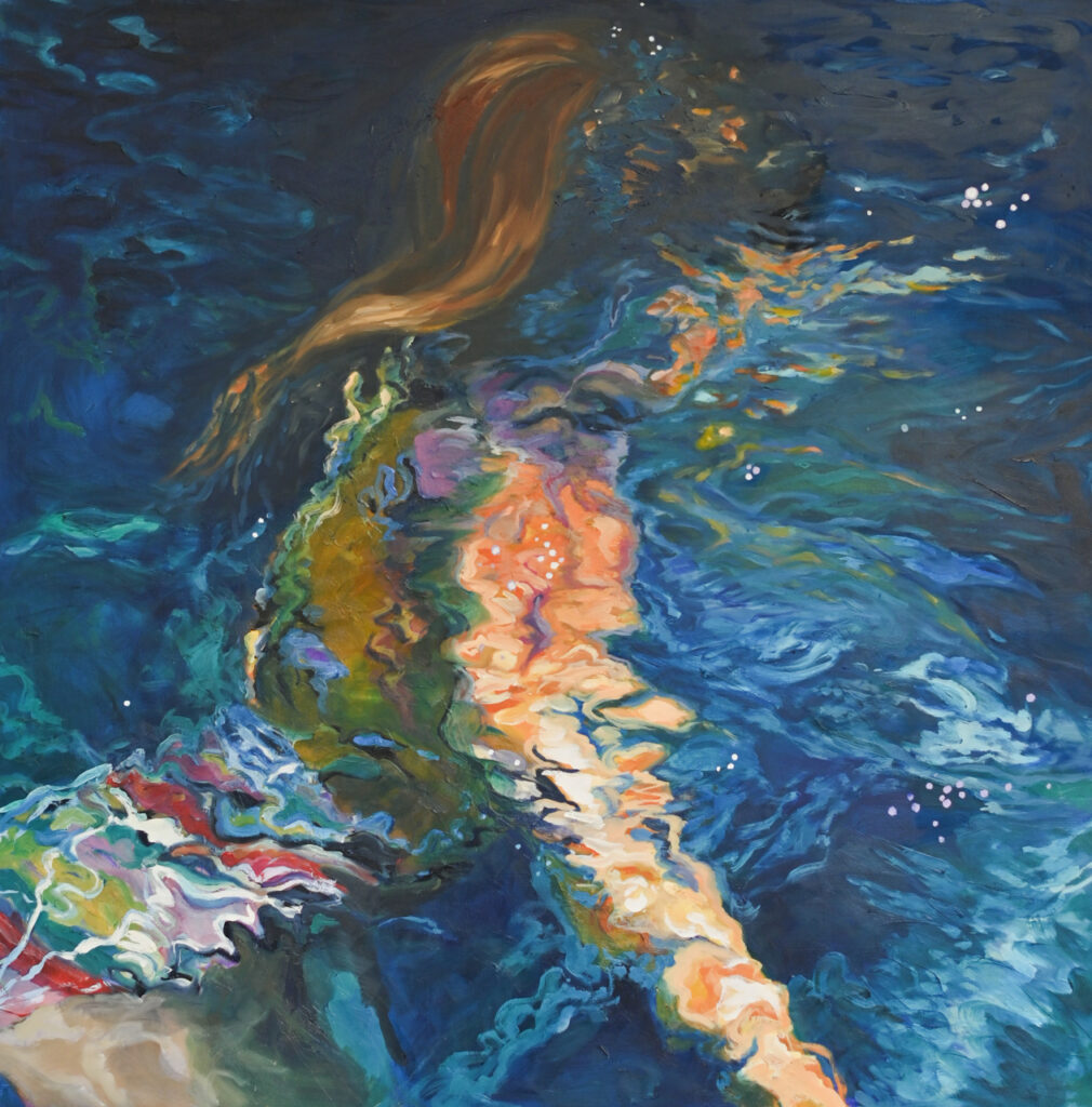 Girl with red hair swimming underwater in deep blue water