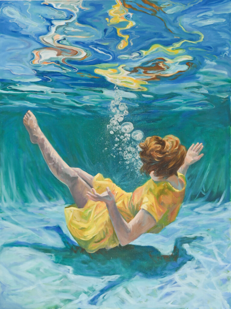 Girl in yellow dress at bottom of a swimming pool with colored reflections on the surface of the water above her.